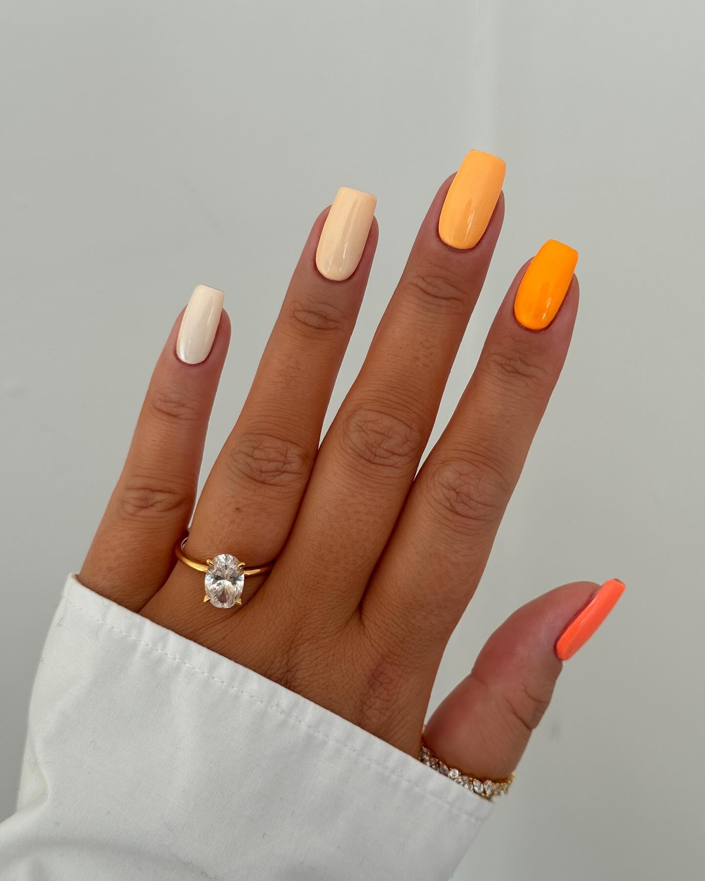 Tonal mix of cream, vivid orange, and coral across each nail