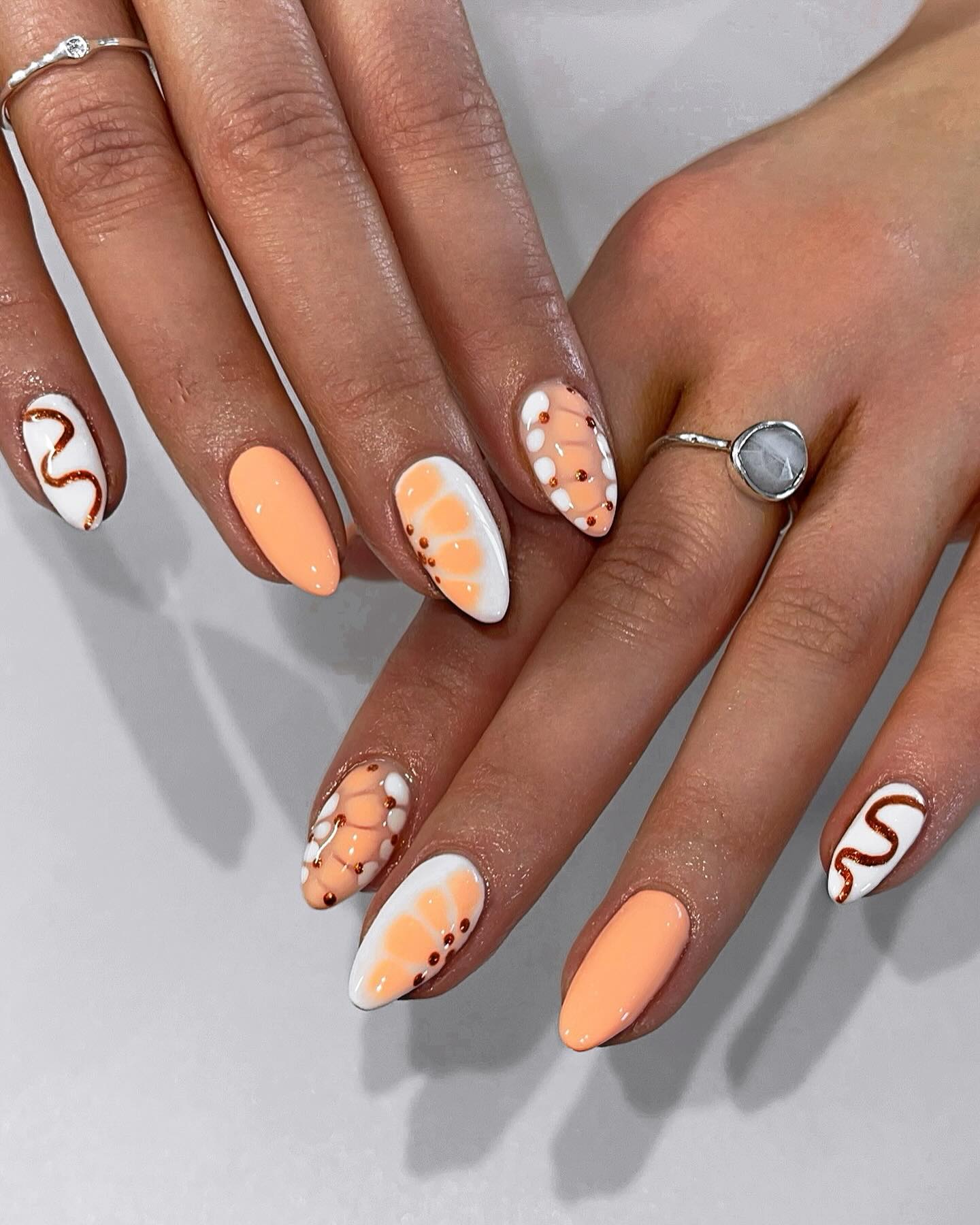 Peach and white nails with swirling burgundy serpent lines and painted daisies