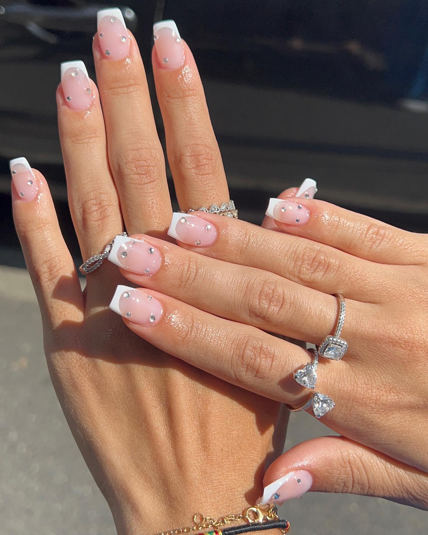 Square nails with white French tips and scattered crystal rhinestones on a sheer pink base