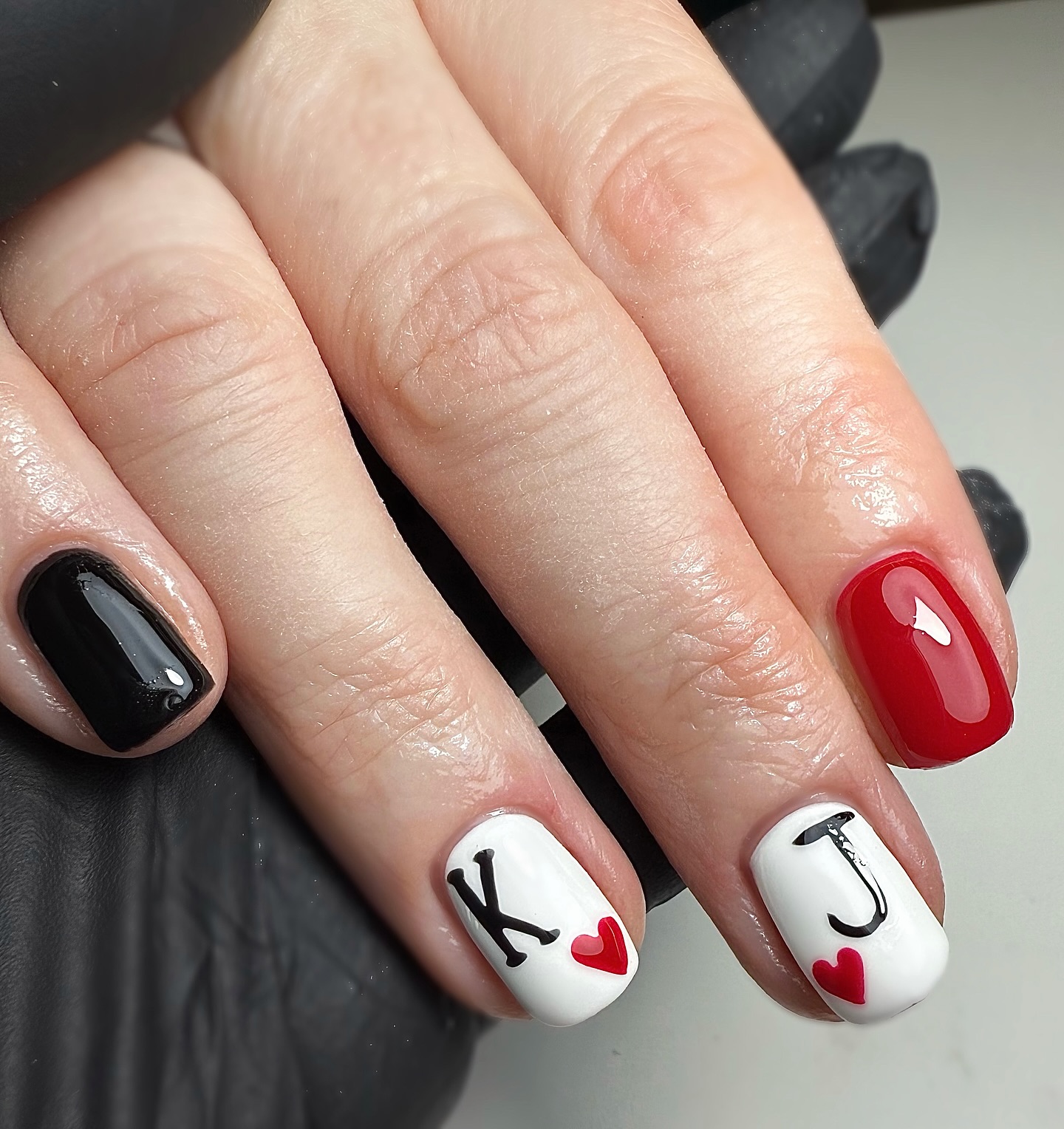 Short square nails in black, red, and white with personalised initials K and J and red heart details