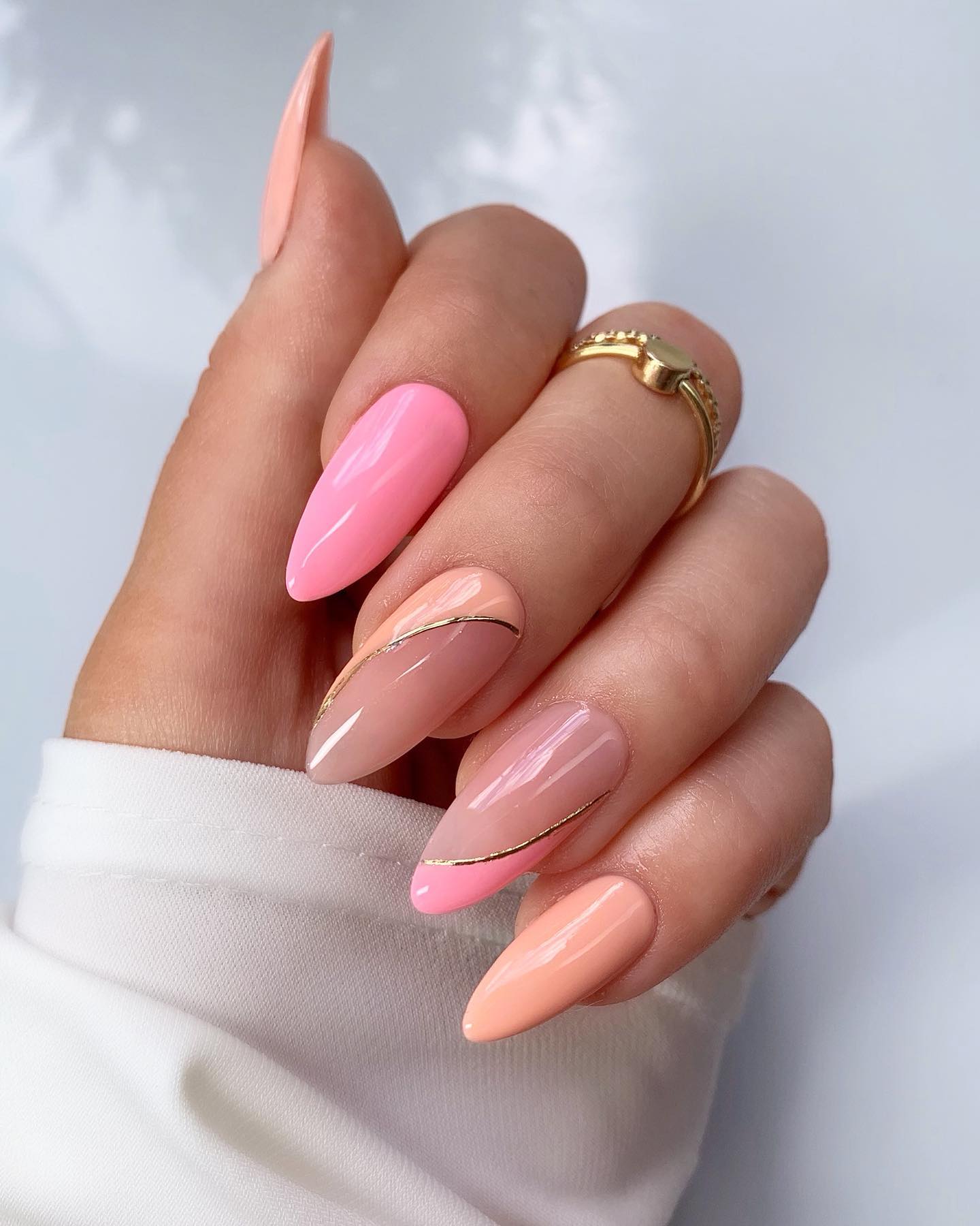 Nails split diagonally between soft pink and peach by a thin gold line