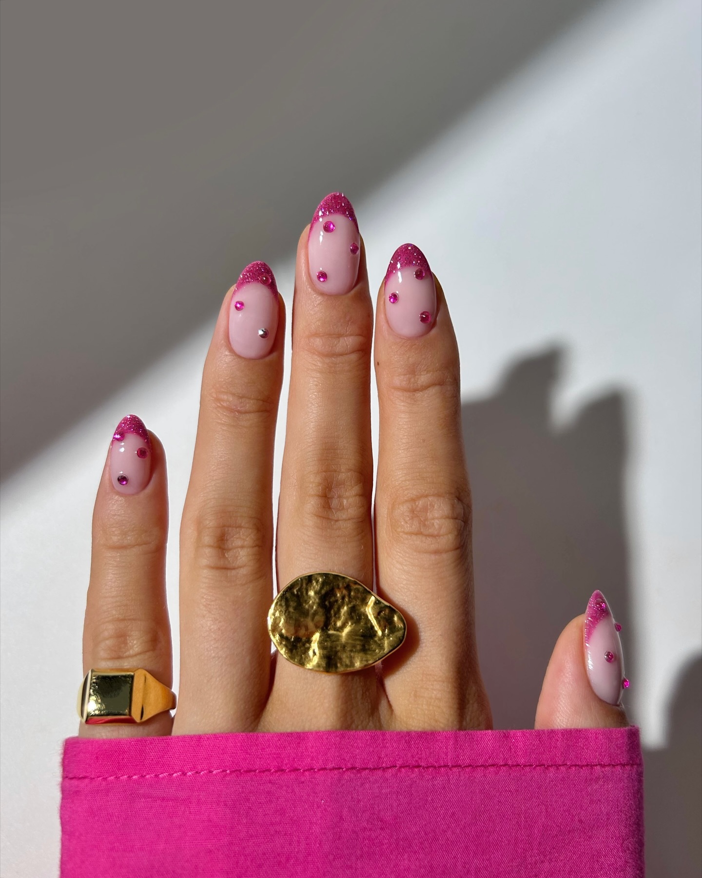 Soft pink oval nails with hot pink glitter French tips and delicate scattered rhinestones