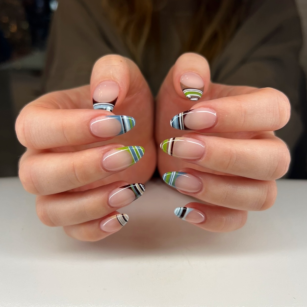 Almond French tips with lime green, blue, and black plaid stripes