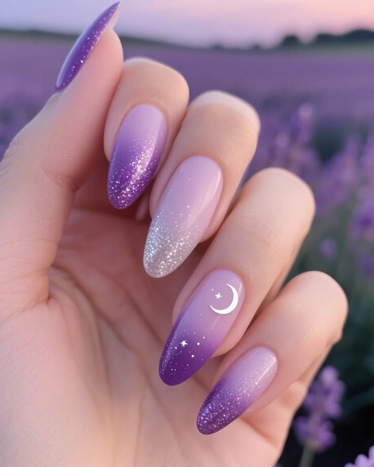 nails with a soft purple to lavender glitter ombre and a white crescent moon charm accent