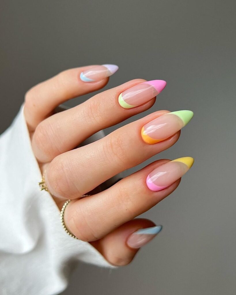 Medium oval nails each with a different pastel tip — lilac, pink, lime green, orange, and yellow