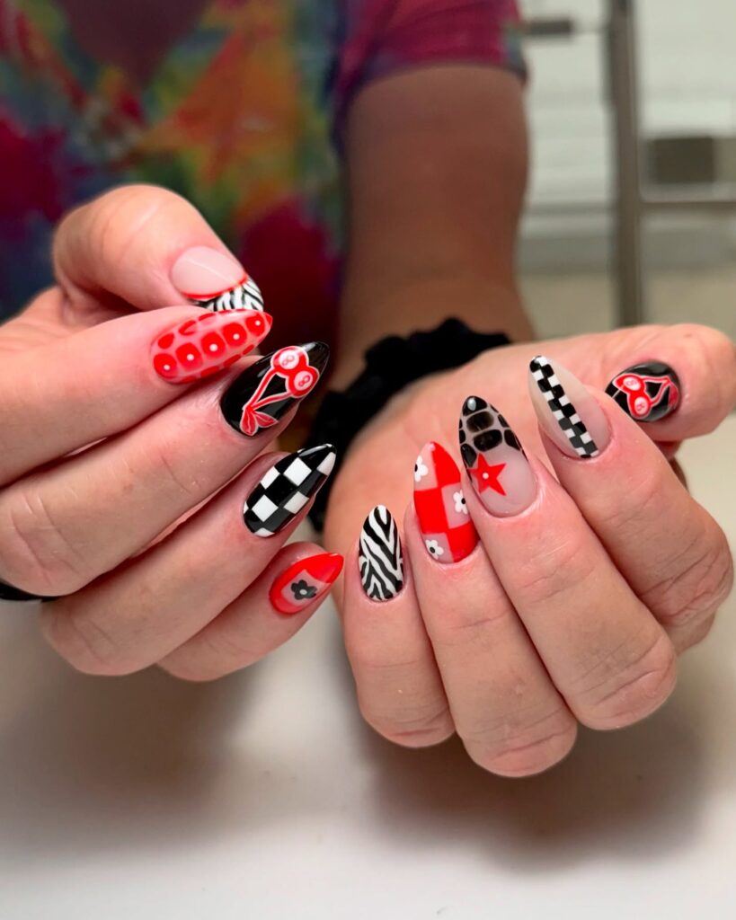 nails featuring a mix of red, black, and white graphic designs, including checkered patterns