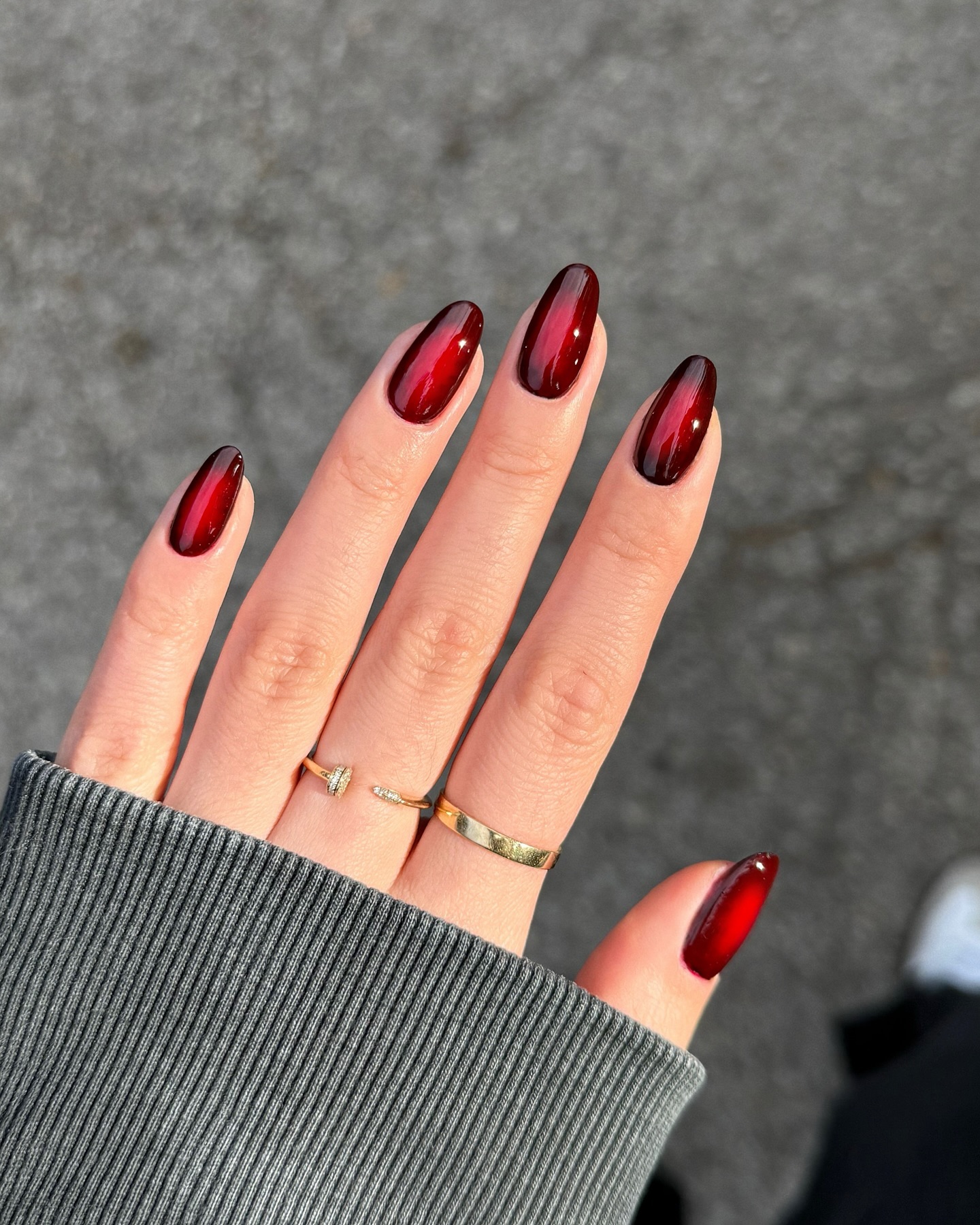 Deep crimson almond nails with black smoky gradient tips and a glossy finish