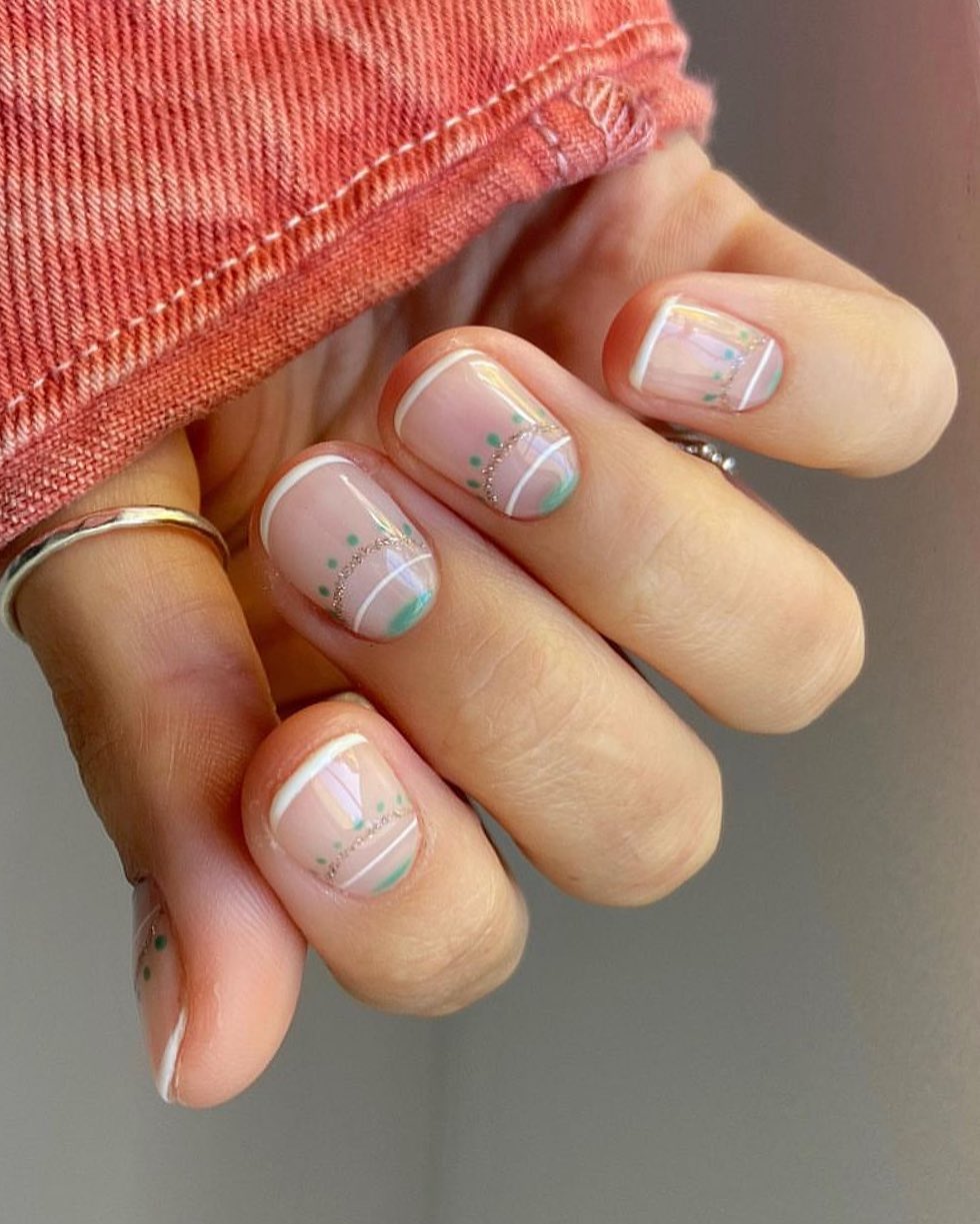 Short square nails with sheer pink base, white French tips, mint green dots, and silver chain detail