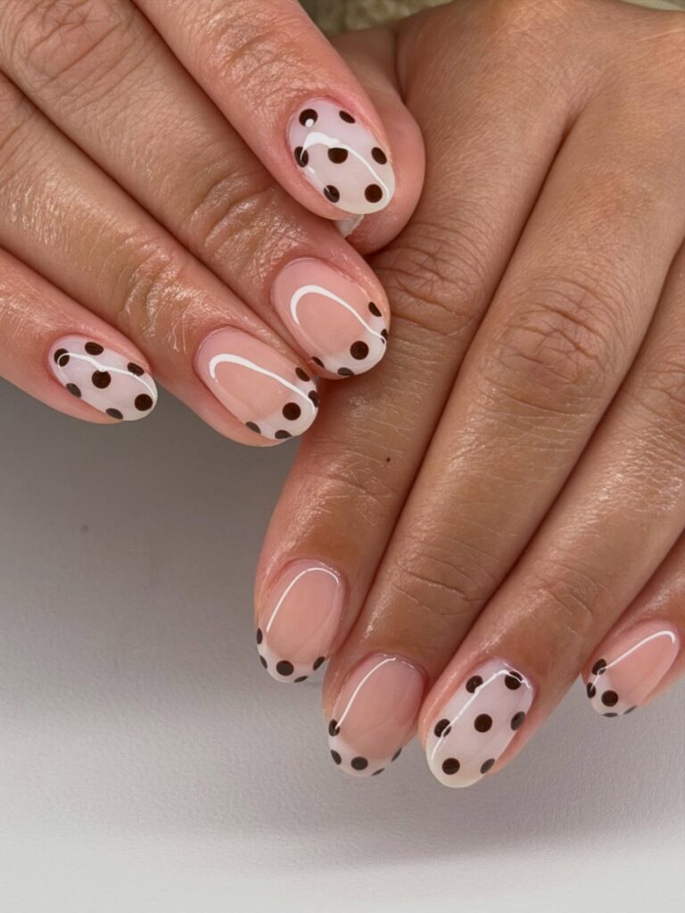 Short oval sheer nude nails with dark chocolate brown polka dots and delicate thin white line arch details
