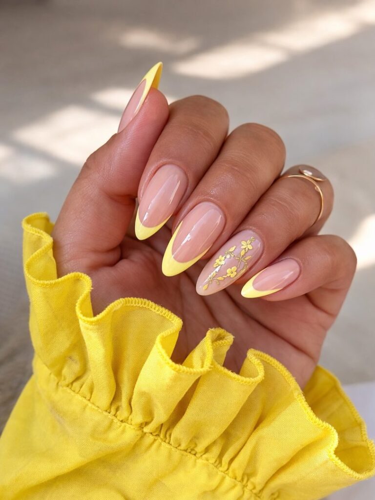 Long oval nails with sunshine yellow tips and one accent nail featuring delicate yellow floral branch detail on a nude base
