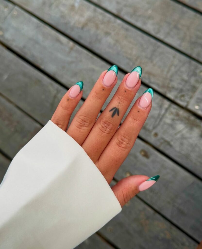 Medium oval nails with metallic teal chrome tips on a sheer nude base