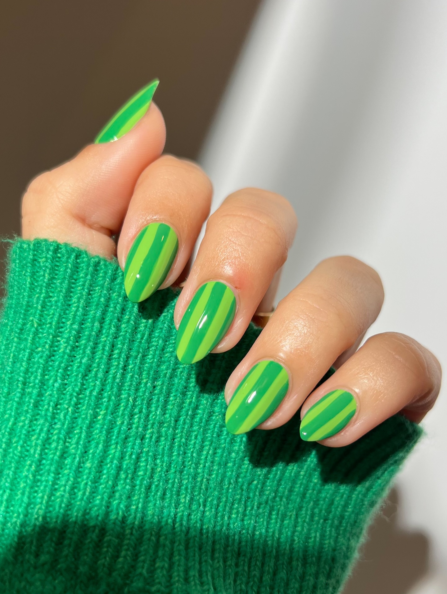 Two-tone green diagonal stripe almond nails with matching knit sleeve