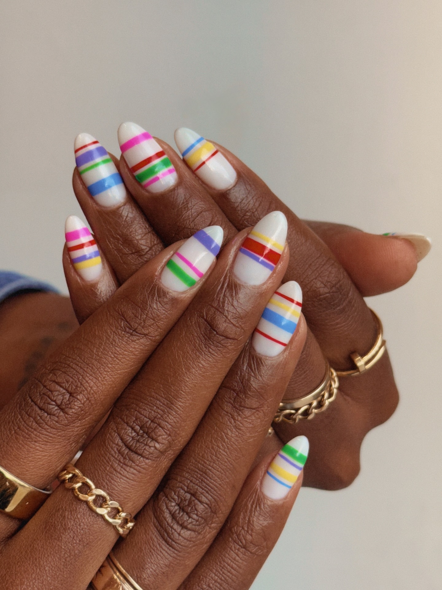 White almond nails with fine multicolour horizontal rainbow stripes