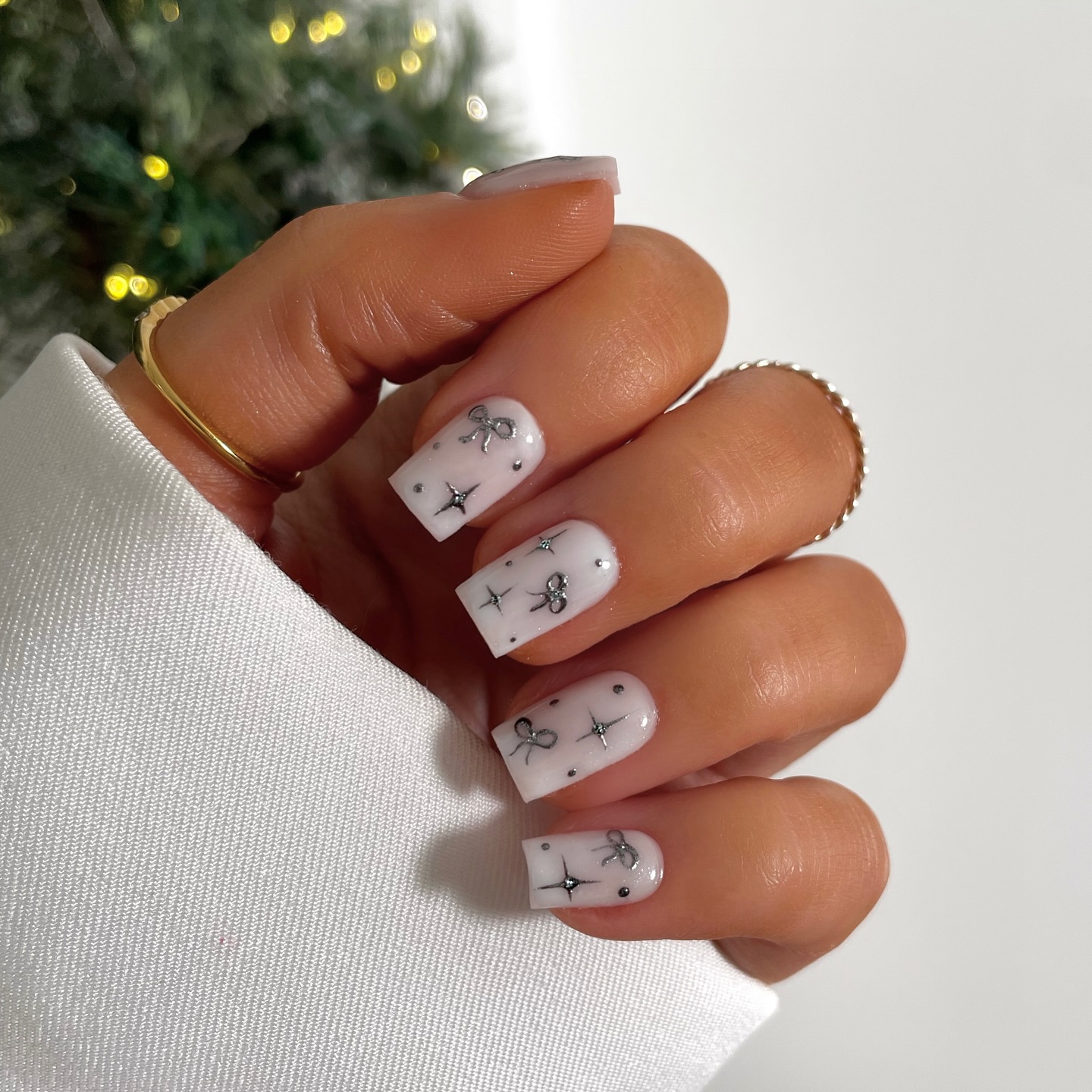 Short white square nails decorated with delicate black star and asterisk nail art