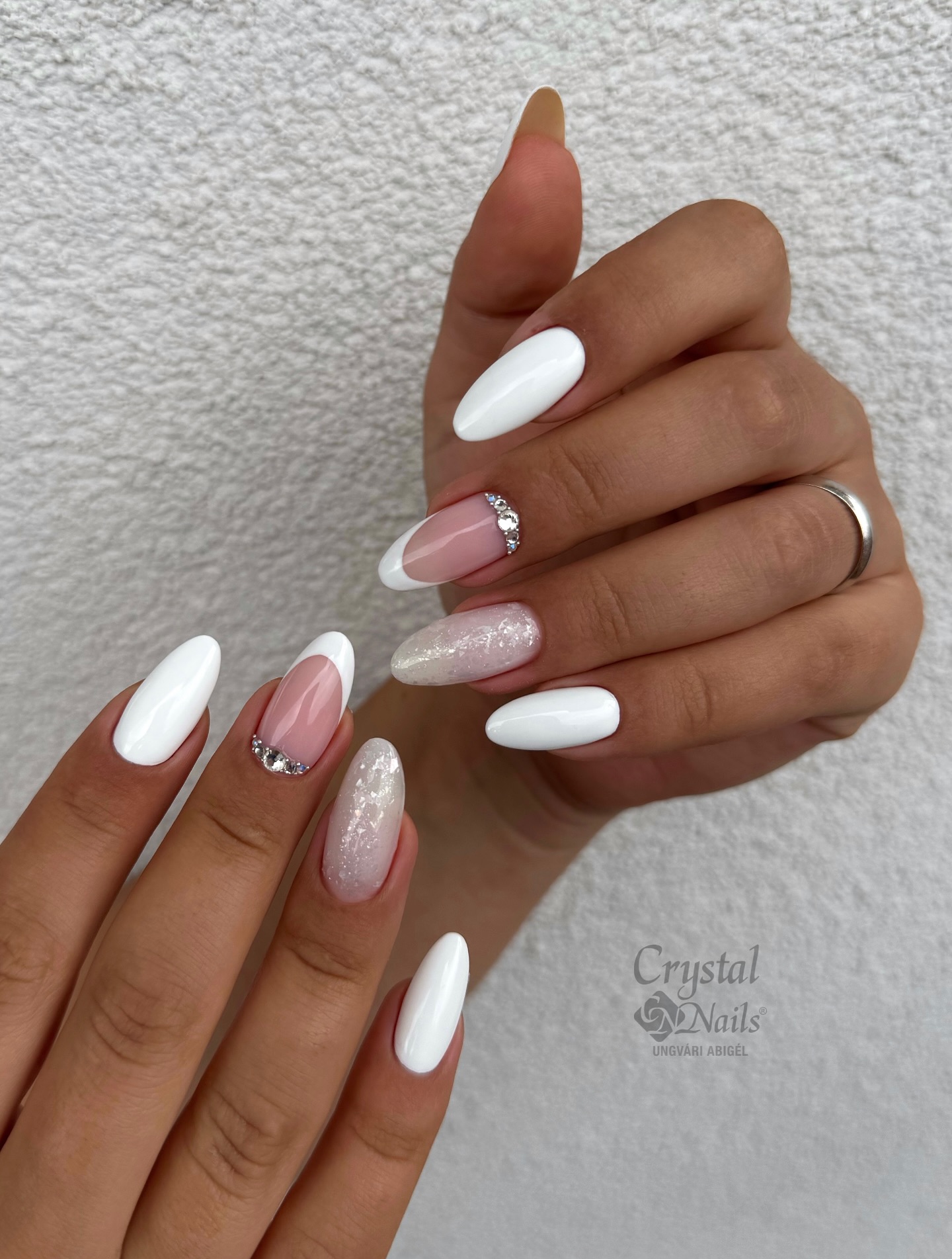 Almond nails in white with a sheer pink glitter accent nail and crystal rhinestone details