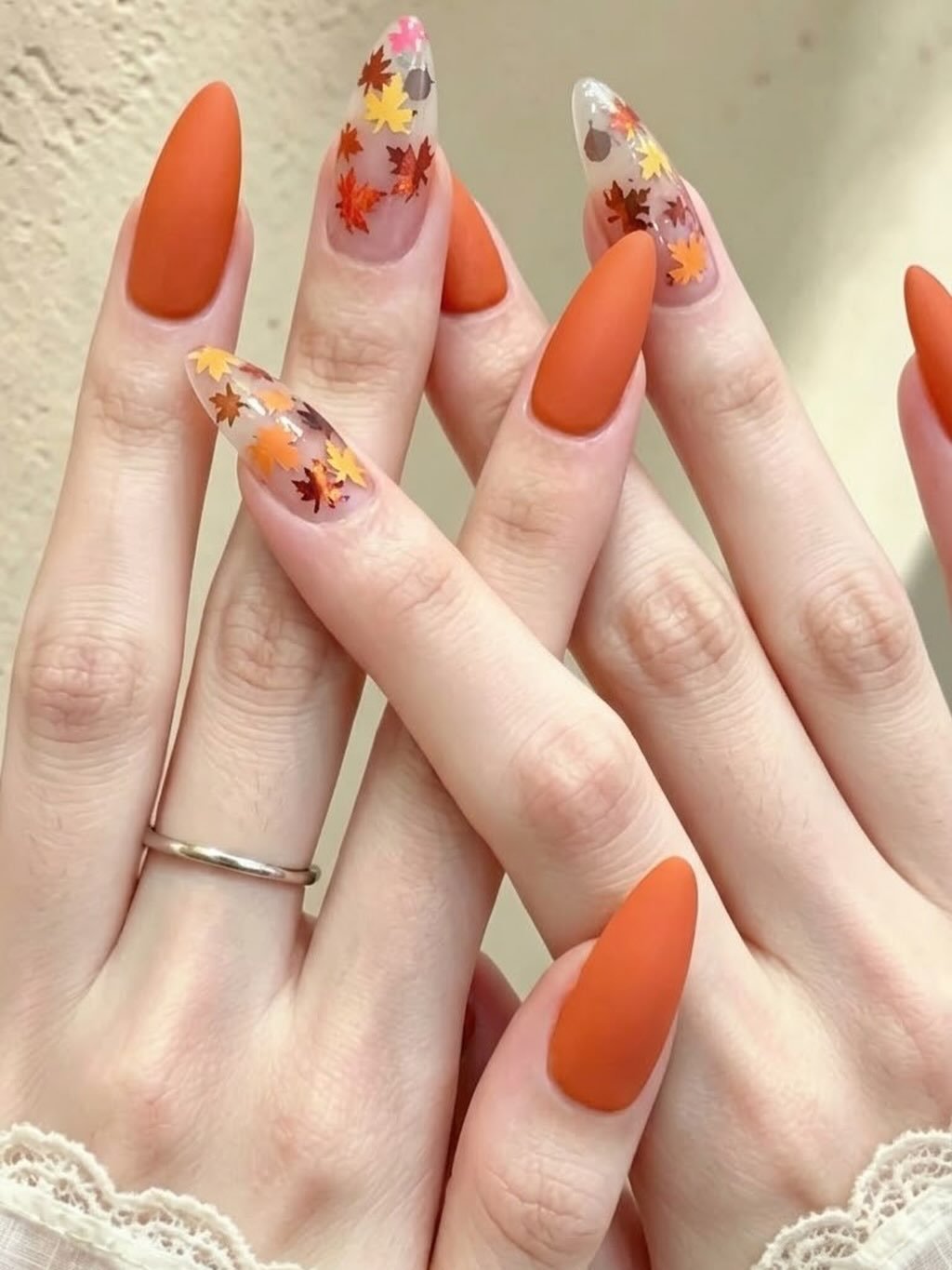 Matte orange almond nails with colorful autumn leaves