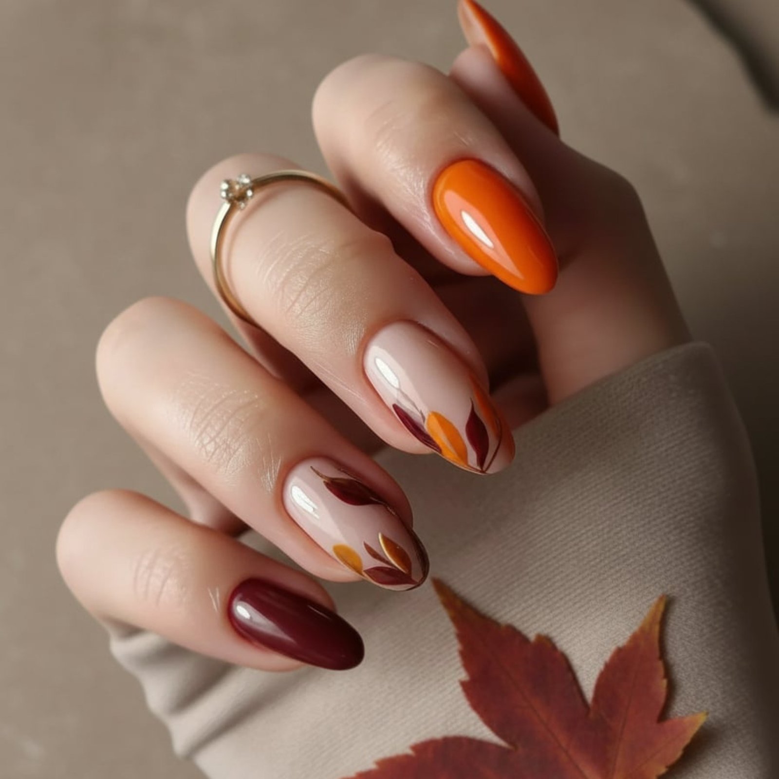 Orange and burgundy almond nails with painted leaves