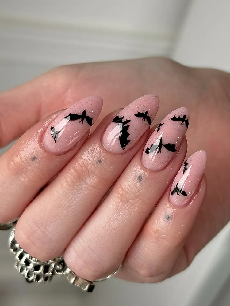 Soft Nude Almond Nails with Black Bats and Tiny Stars