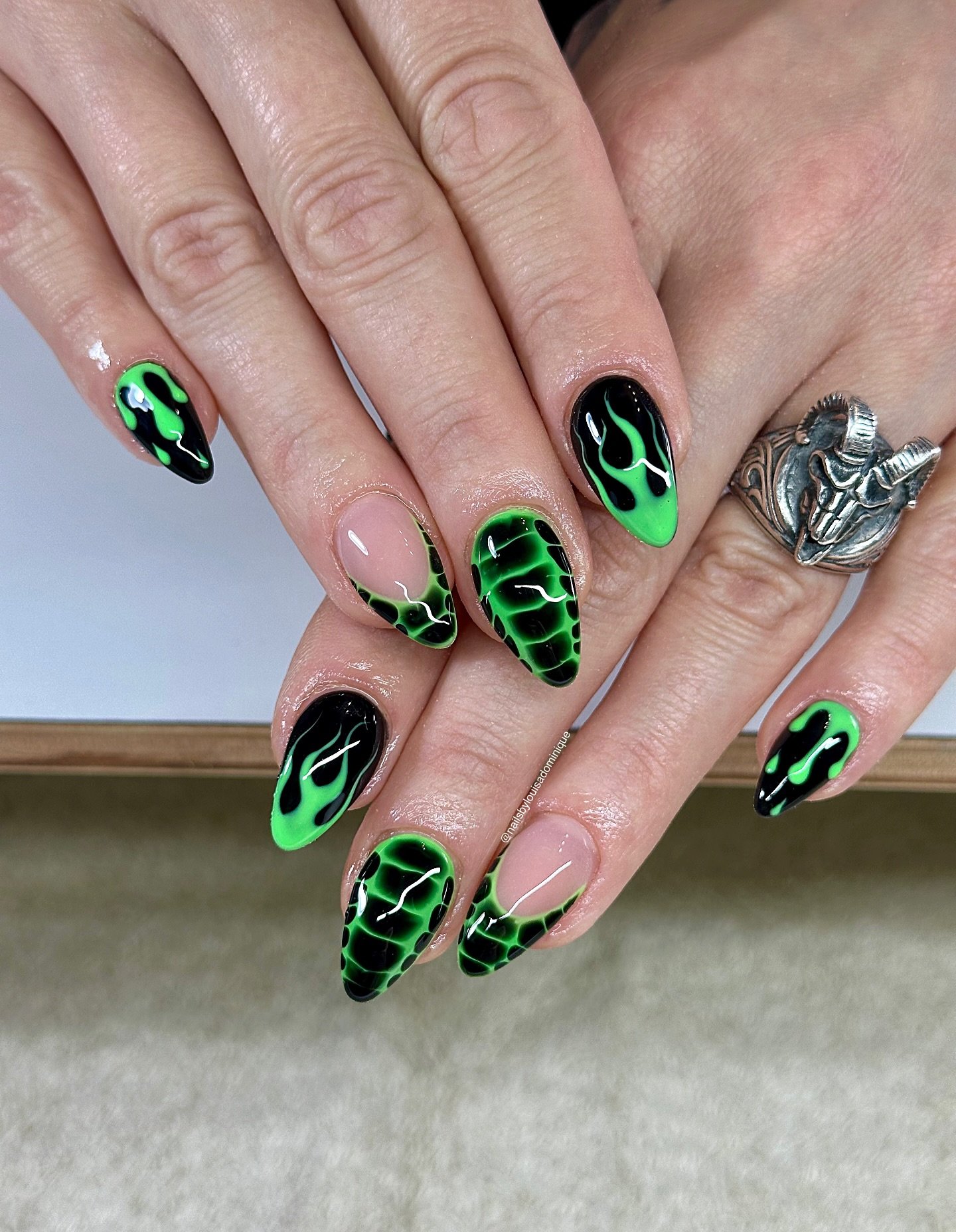 Almond nails pair black polish with bright green graphic details and small contrasting linework