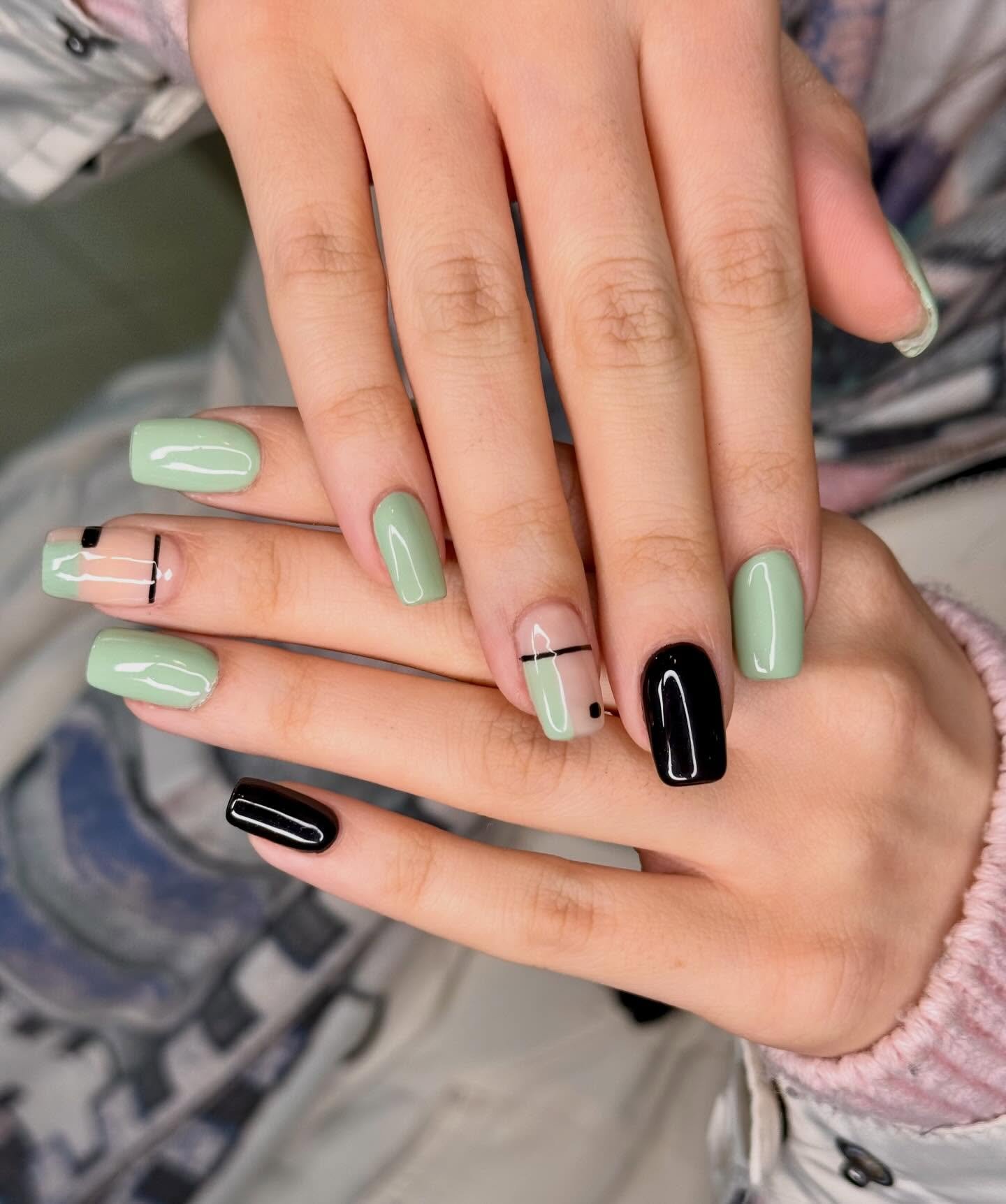 Medium-length nails mix soft mint green, black, and plaid-style accent details in a contrasting manicure