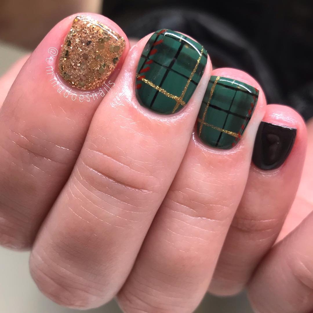 Short square nails feature dark green plaid panels alongside black nails and one textured gold accent
