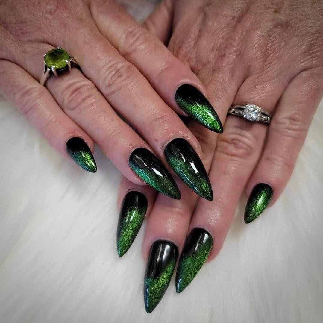 Long stiletto nails are coated in a rich deep green with dark black shading and a glossy finish