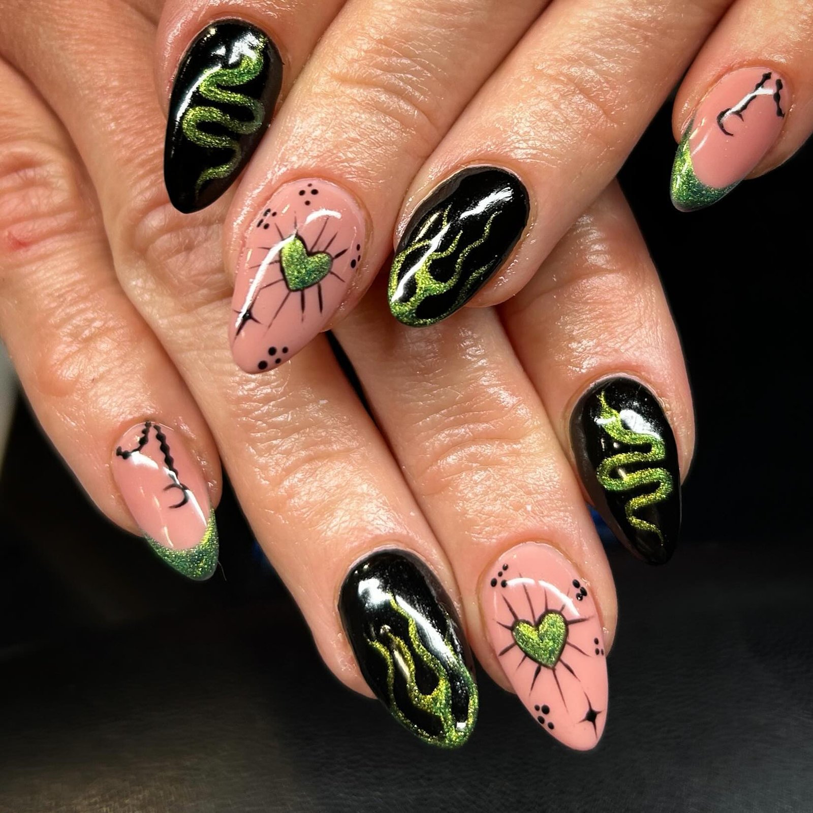 Short almond nails mix black and soft pink bases with vivid green and black graphic linework