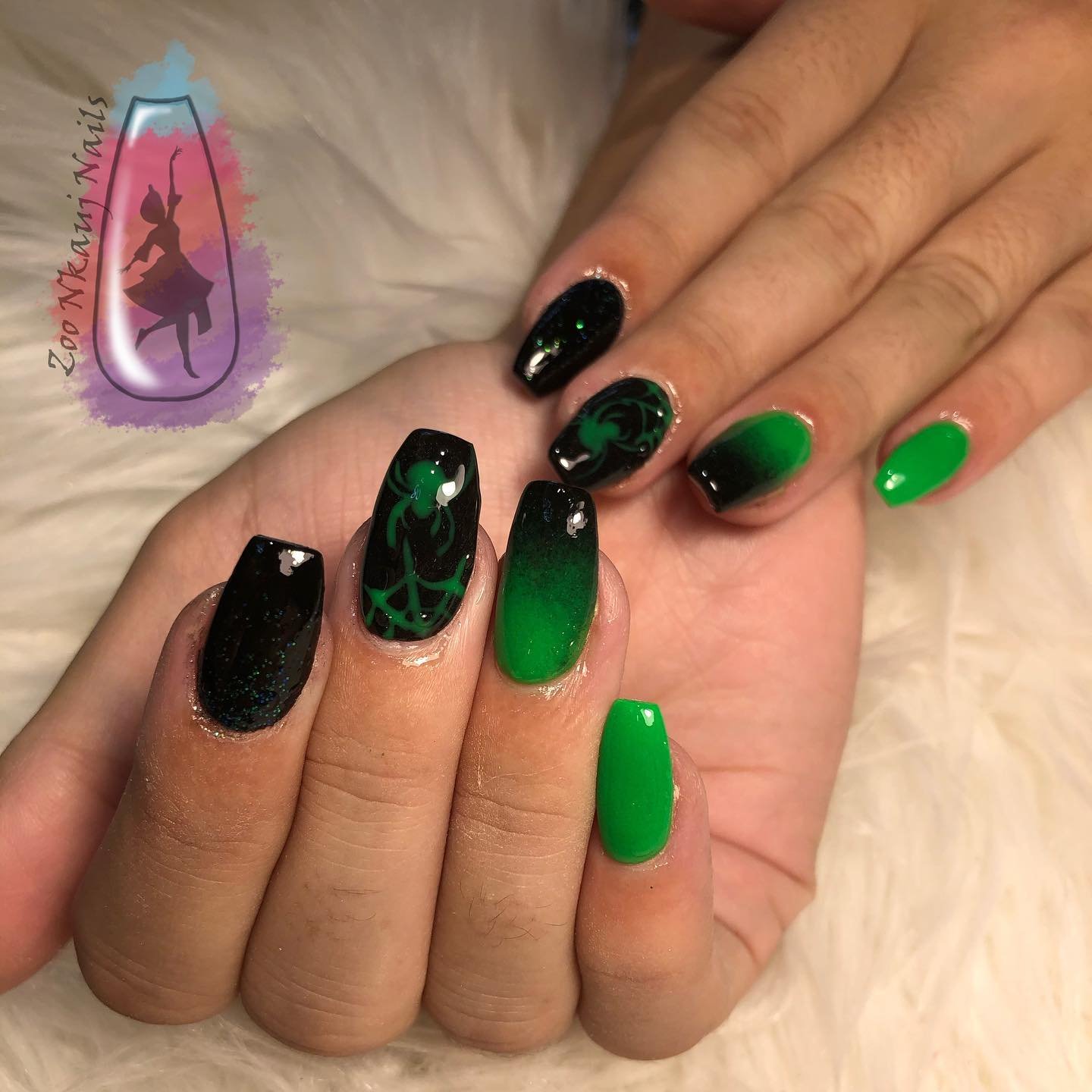 Medium-length nails alternate glossy black and bright green, with one translucent accent containing a small decorative detail