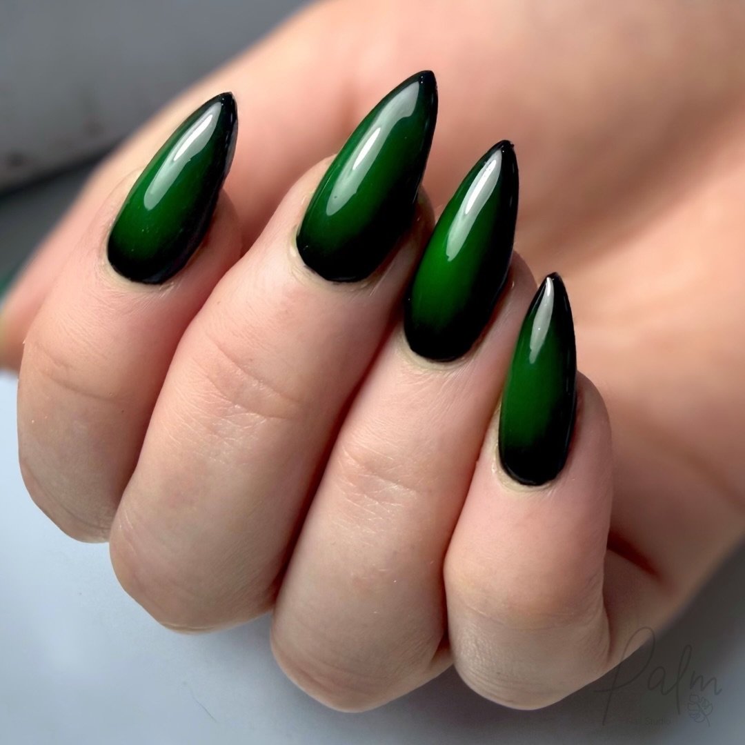 Long almond nails are finished in a smooth, glossy deep green shade