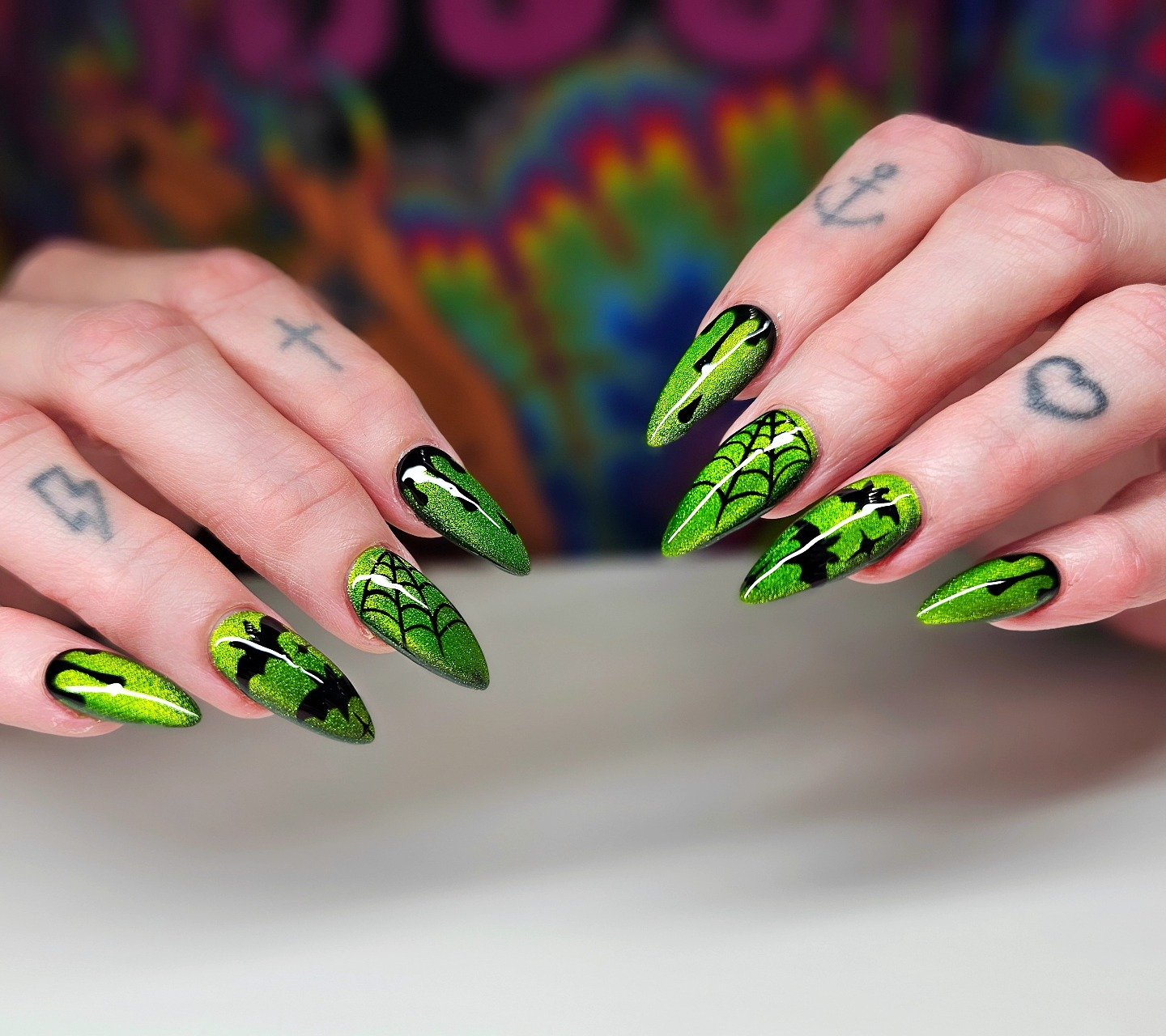 Long nails mix neon green and black with bold pointed graphic motifs and contrasting line details