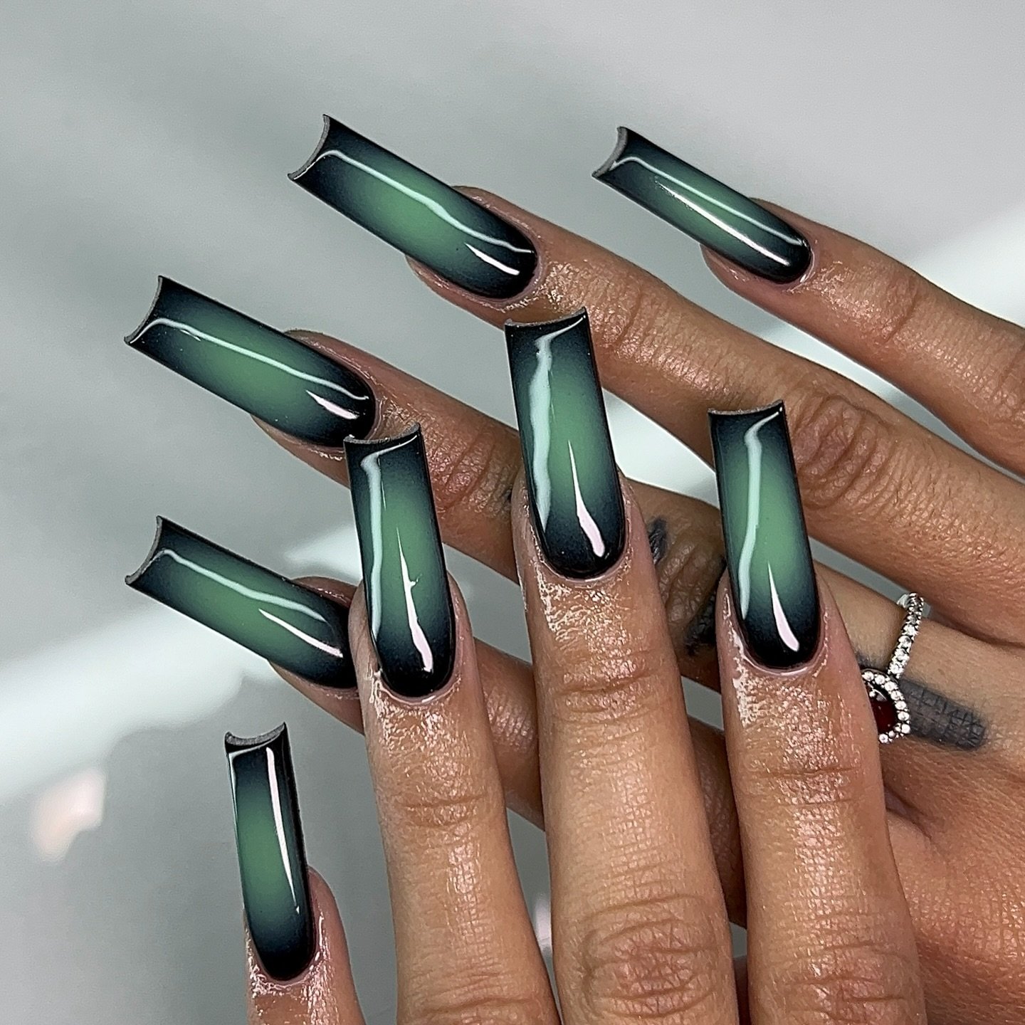 Long coffin-shaped nails combine dark green and black with bright reflective stripe details