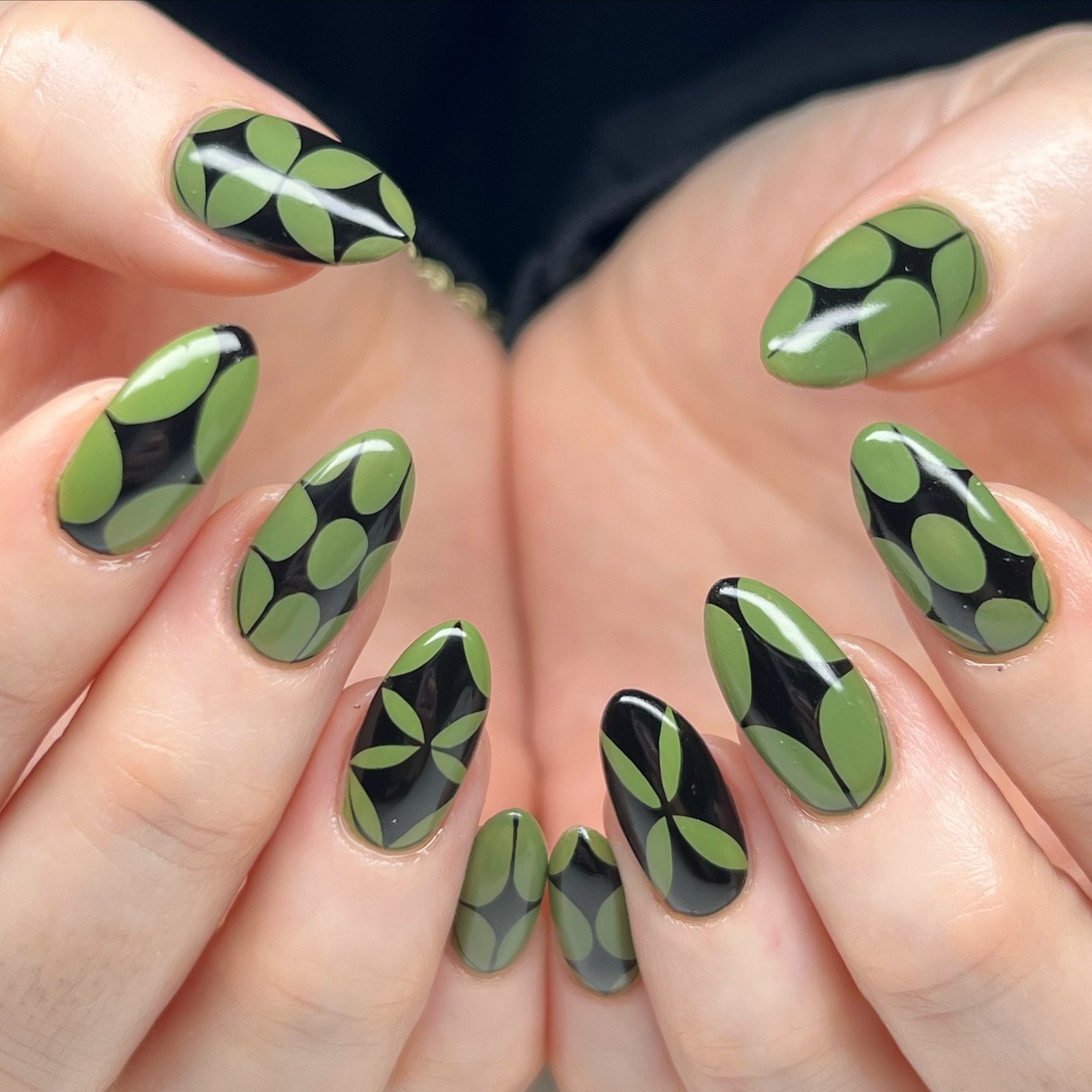 Short almond nails use a light green base with dark green and black rounded petal-like patterns