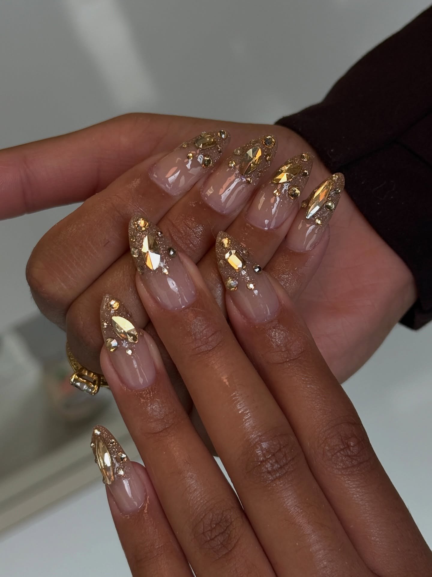 Long Nude Nails with Gold Embellishments and Rhinestones