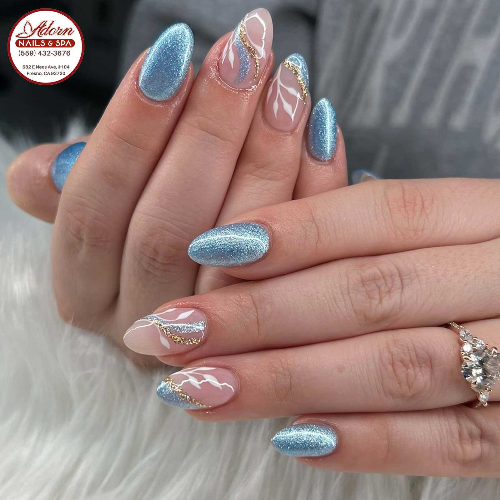 Blue Christmas nails idea 3: Icy Blue Shimmer Almond Nails with Silver-White Swirls
