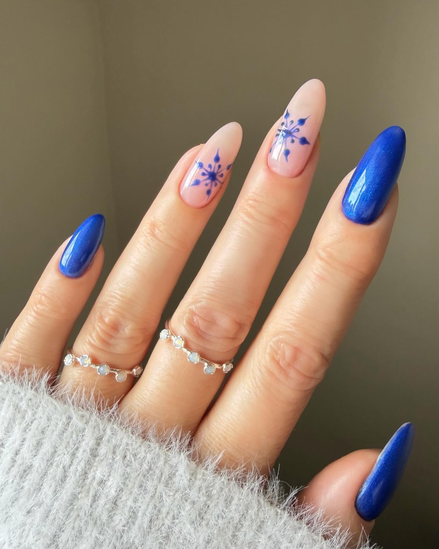 Blue Christmas nails idea 12: Royal Blue Almond Nails with White Snowflakes and Sweeping Lines