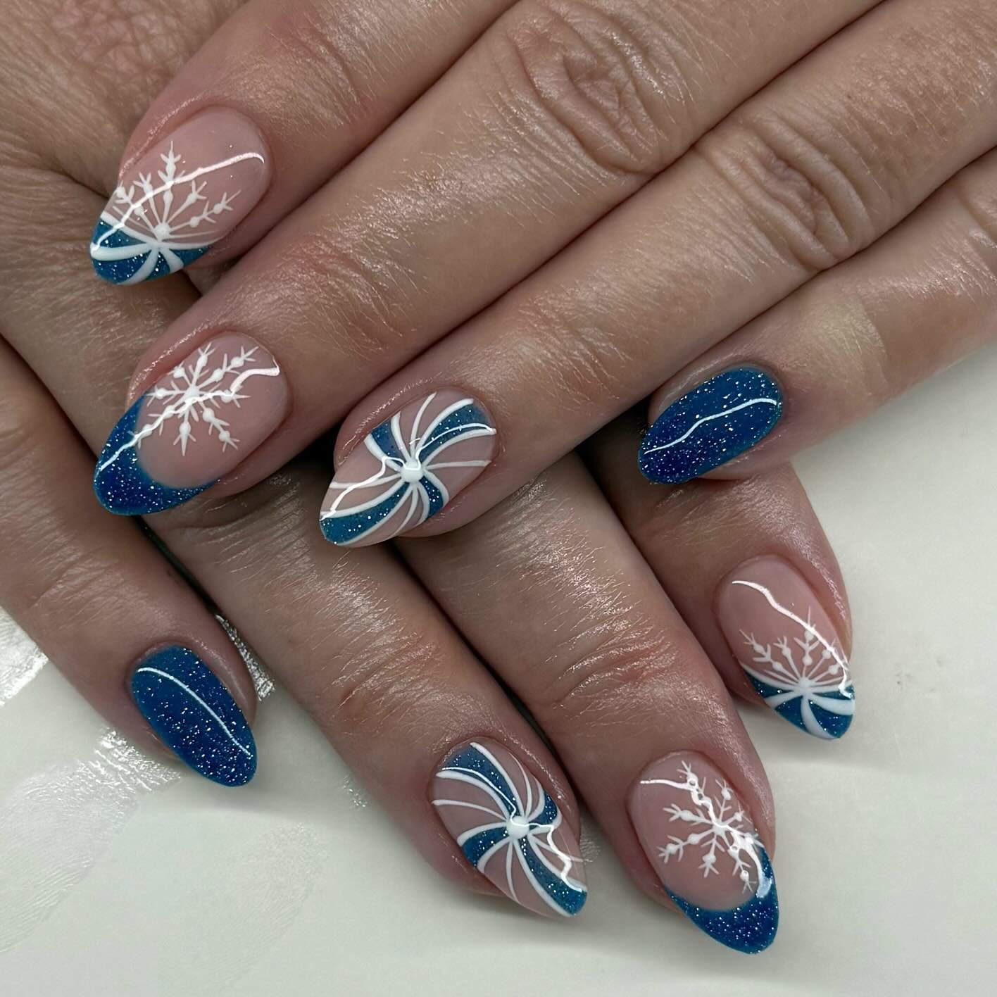 Blue Christmas nails idea 14: Blue Glitter Almond Nails with Snowflakes and Candy-Cane Lines