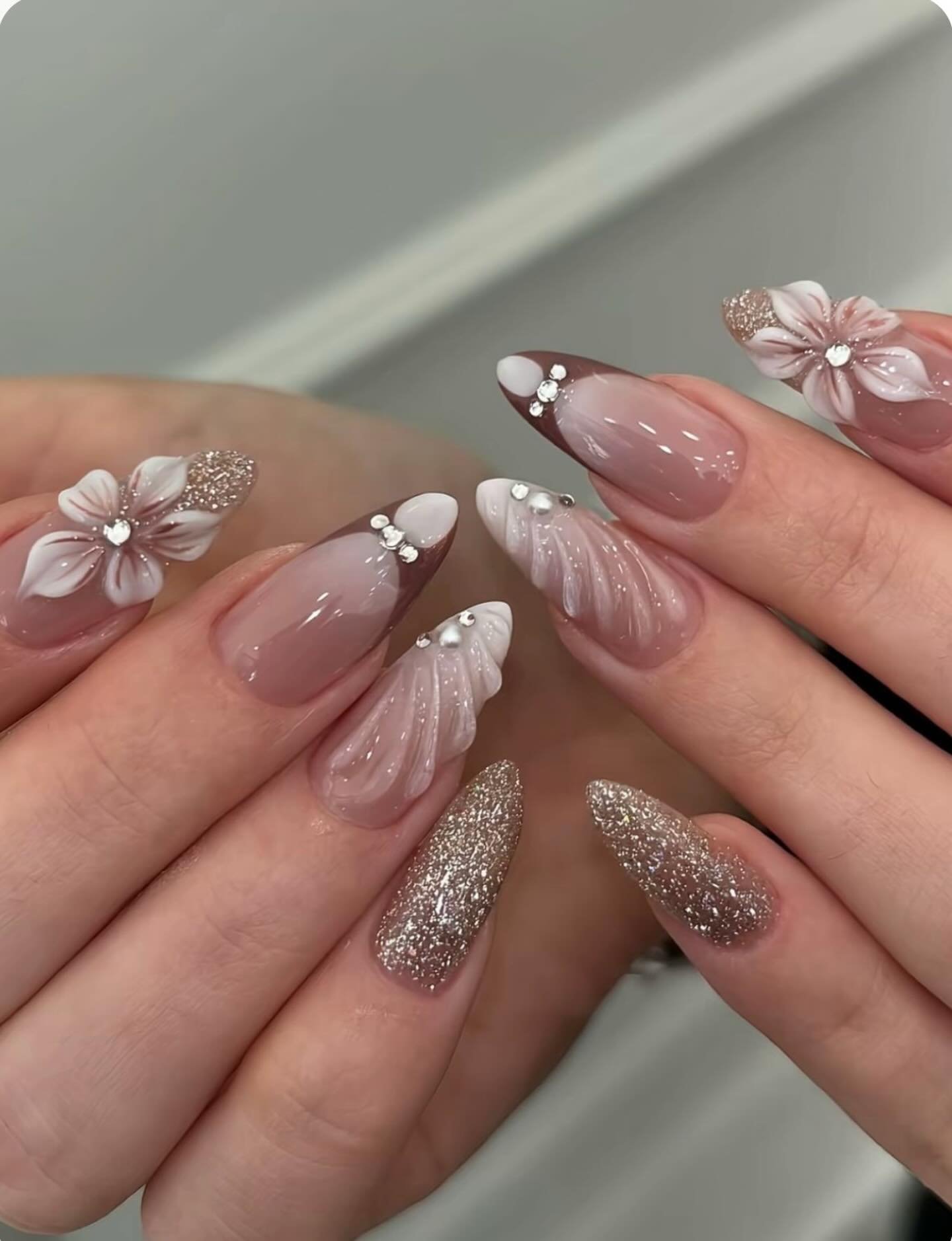 Blush Almond Nails with White Flowers and Glitter Accents