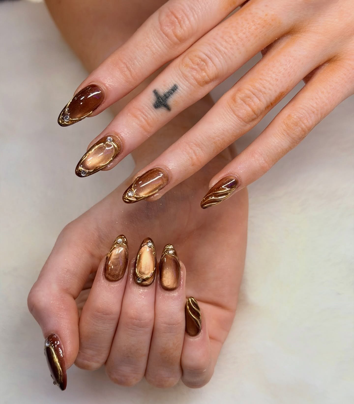 Bronze Almond Nails with Gold Outlining and Swirls