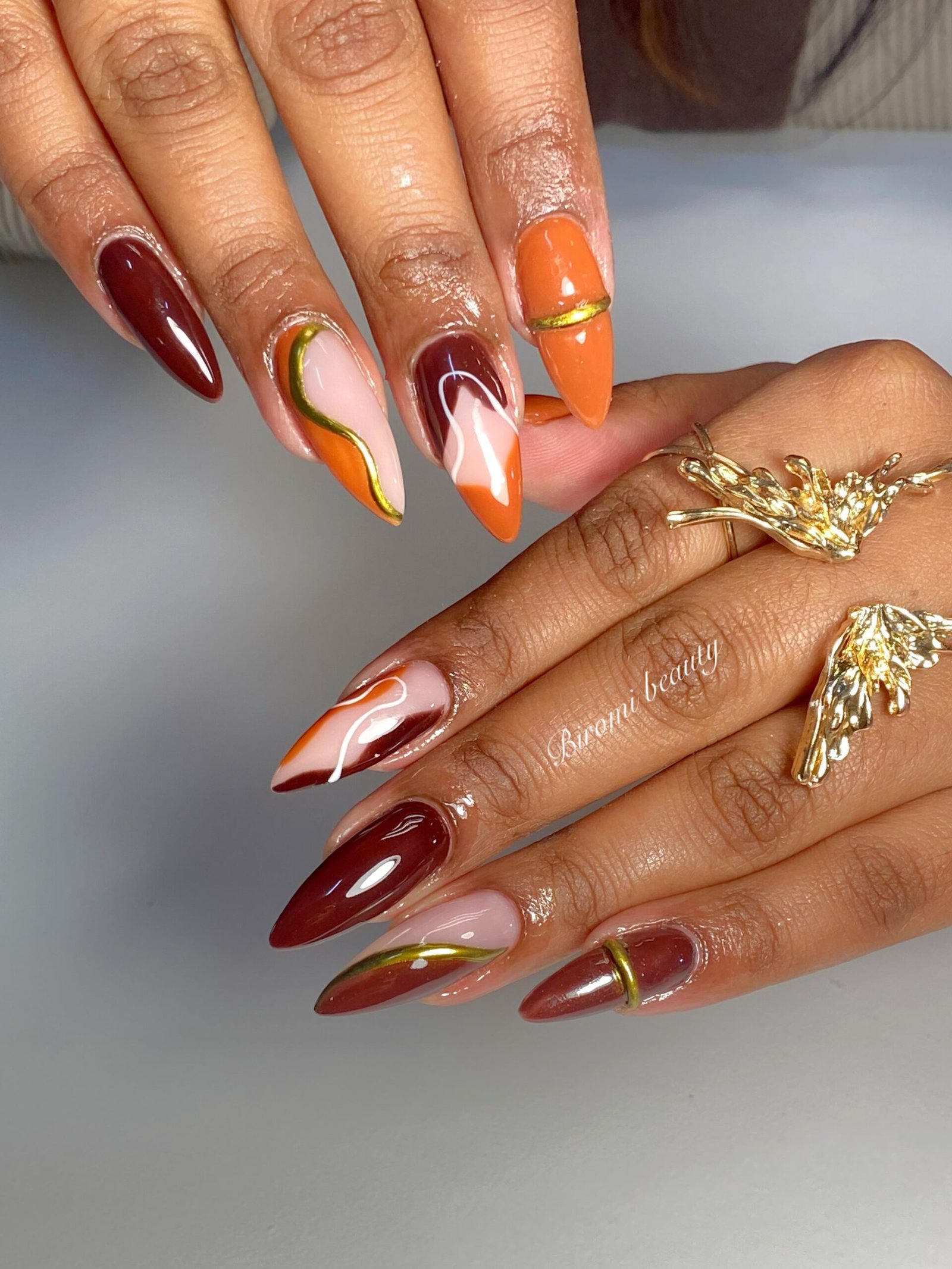 Burgundy, Orange, and Gold-Toned Almond Nails