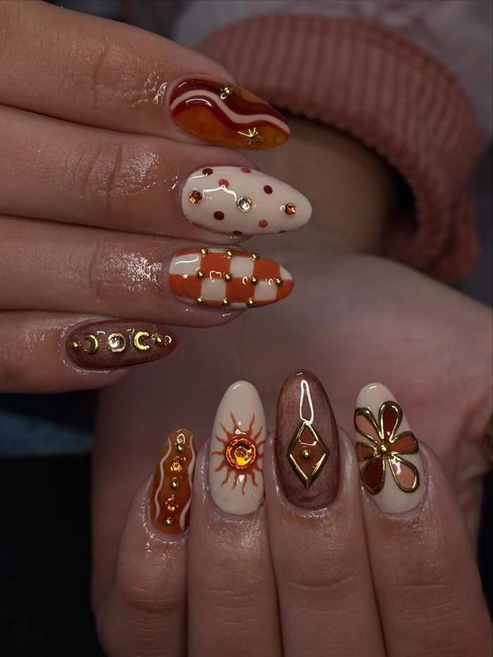 Neutral Almond Nails with Burnt Orange Swirls and Embellishments