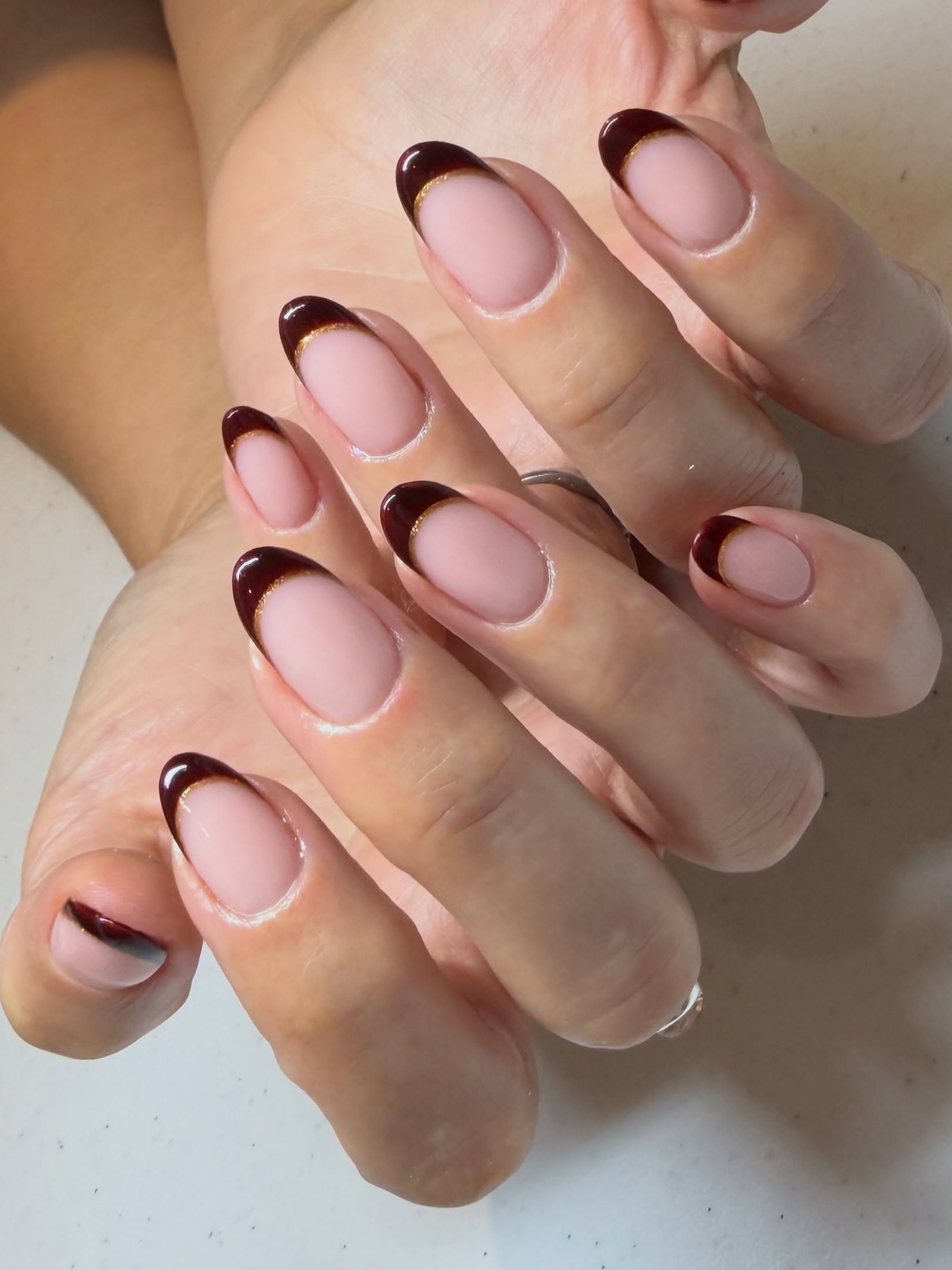 Medium almond nails keep the look simple with a sheer pink-nude base and chocolate-brown French tips.