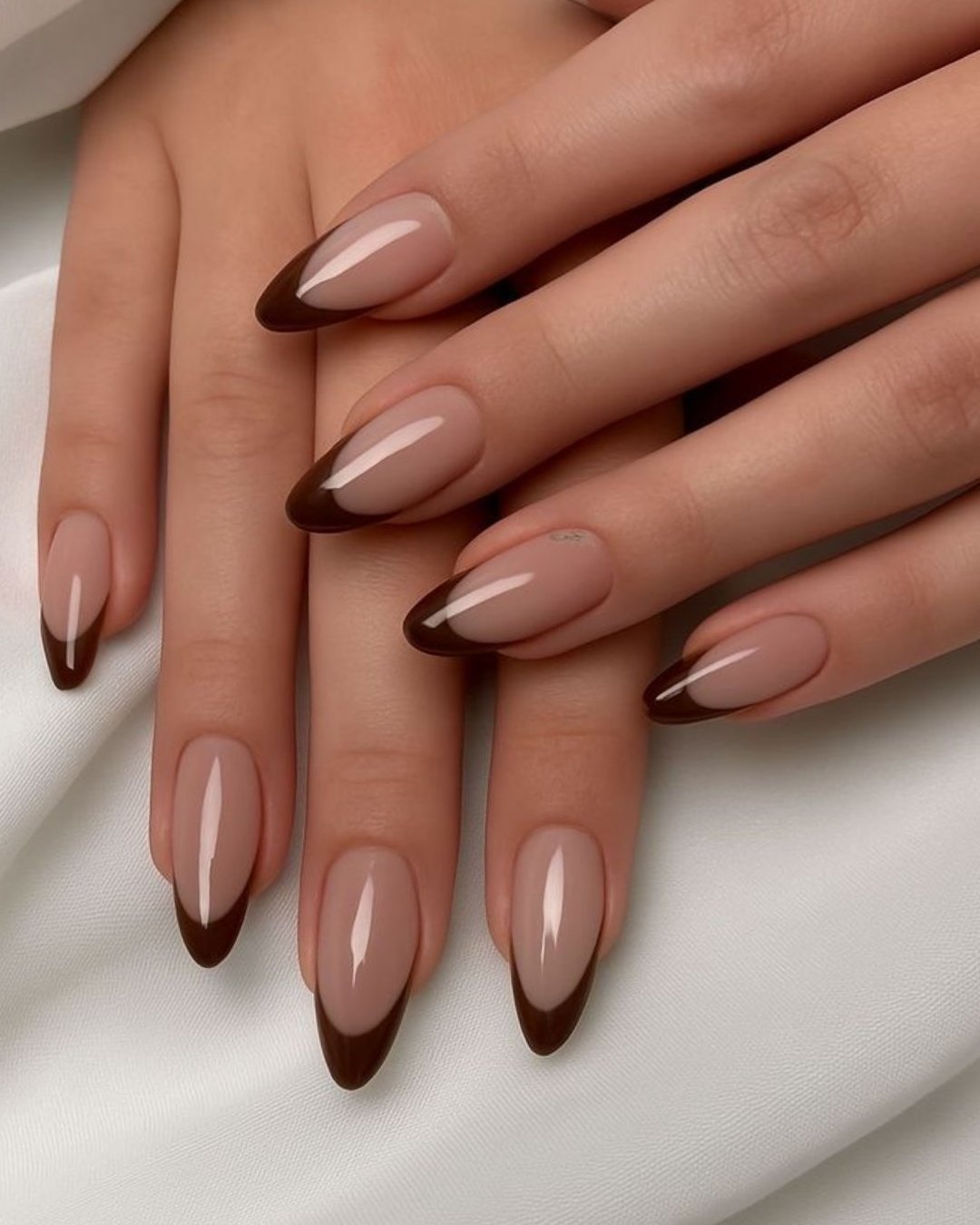 Medium almond nails combine a glossy blush-nude base with dark chocolate-brown French tips.