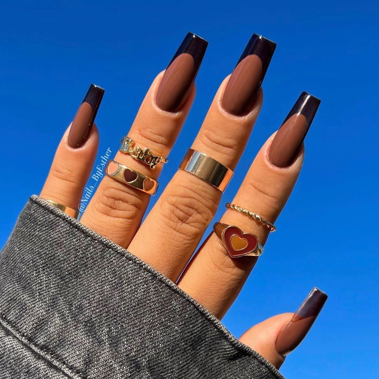 Long square nails feature a warm nude base and bold, dark chocolate-brown French tips.