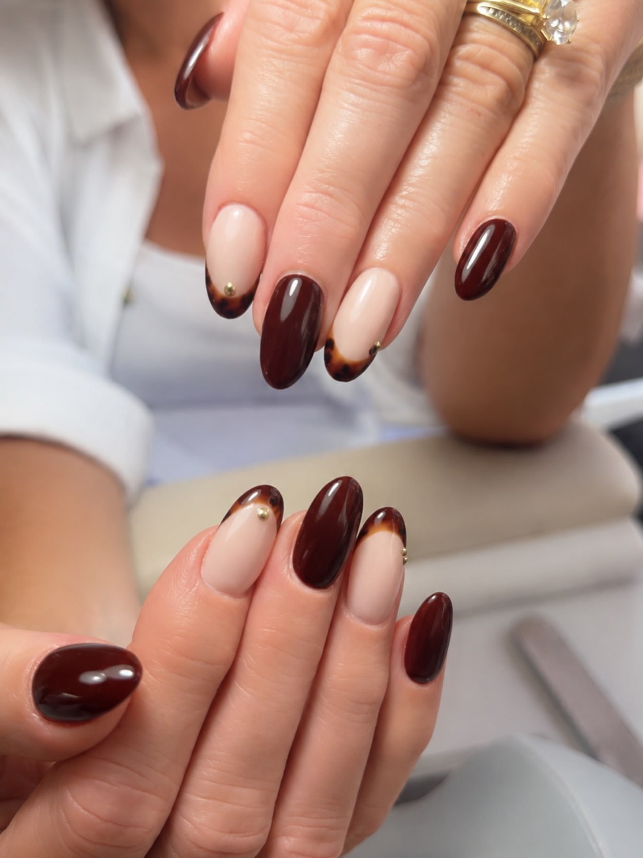Short almond nails feature a natural nude-pink base with deep chocolate-brown French tips.