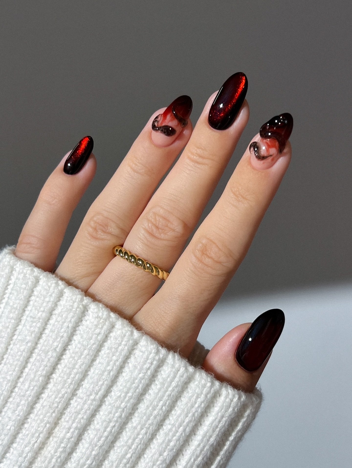 Dark burgundy almond nails with black-tipped accent details