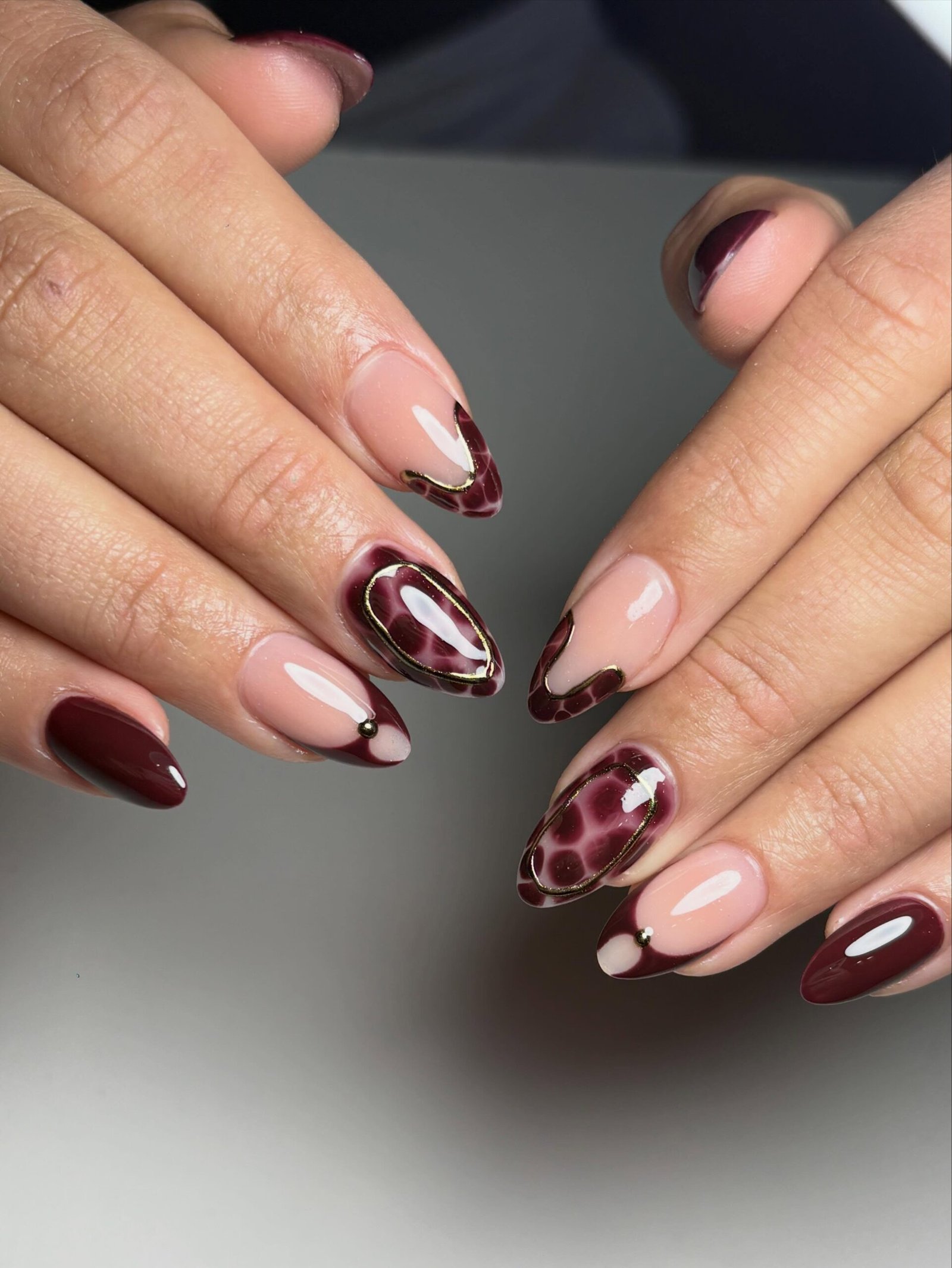 Burgundy almond nails with patterned accent details