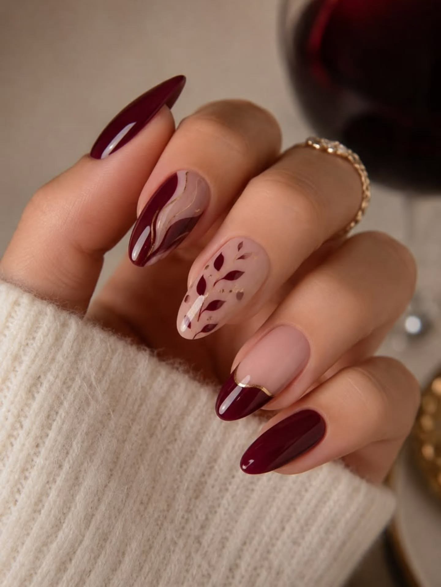 Deep burgundy almond nails with a nude floral accent