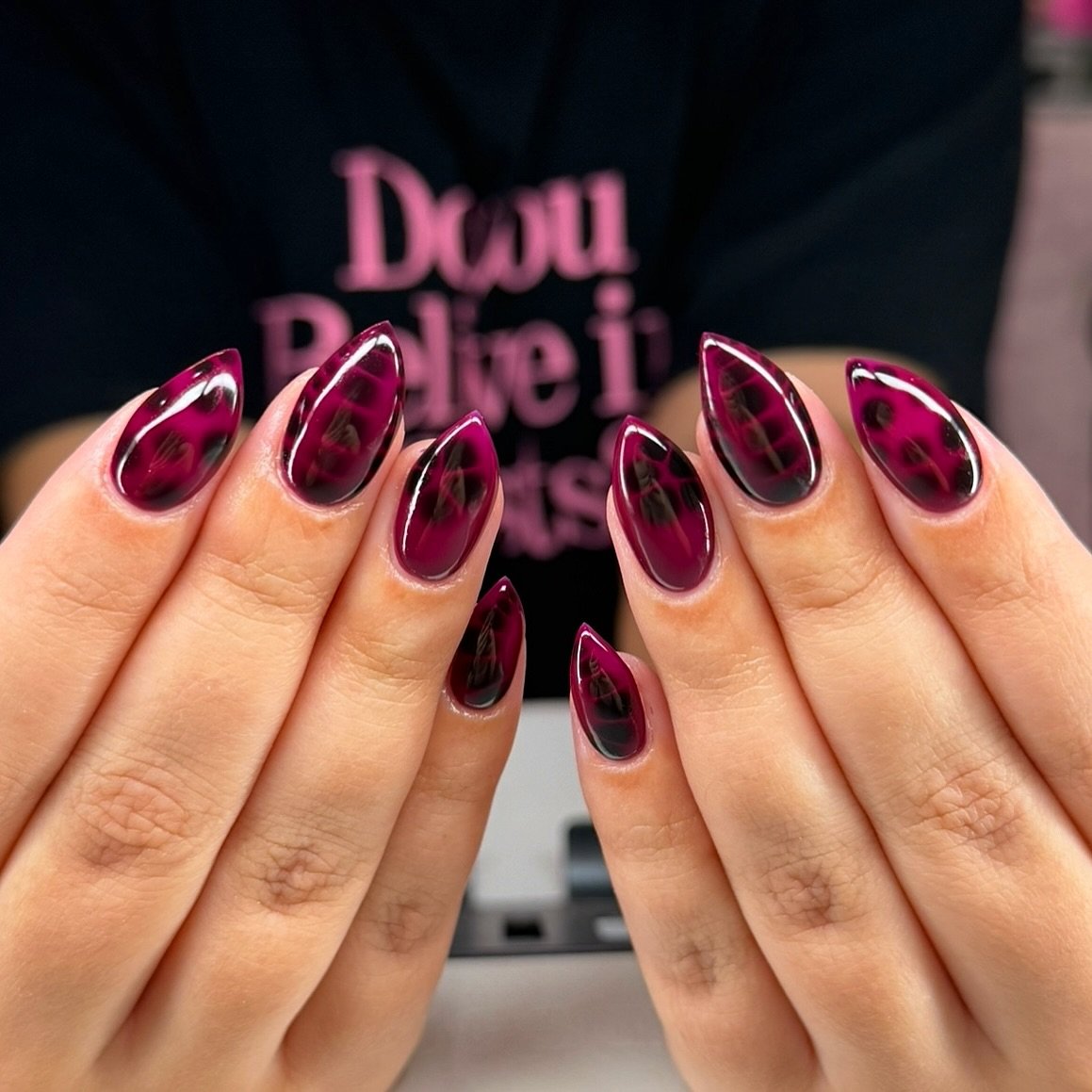 Glossy burgundy almond nails with a bright pink reflective finish