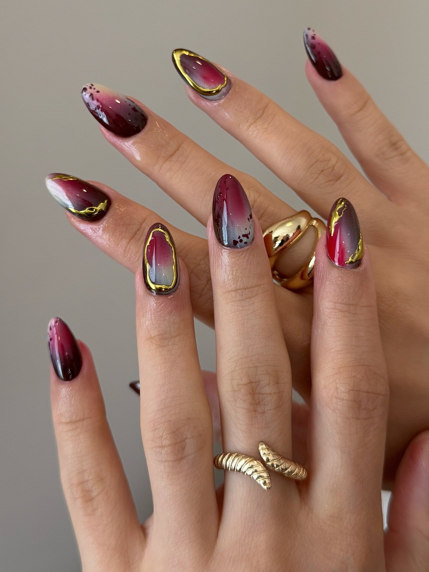Mixed burgundy almond nails with metallic gold accents