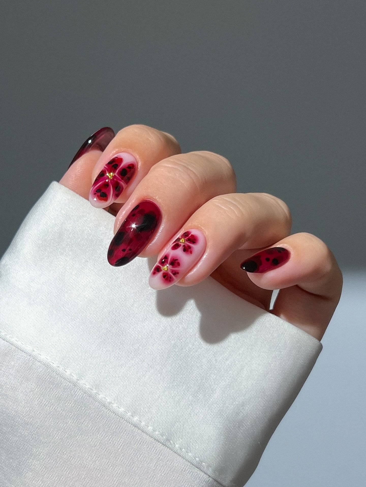 Burgundy almond nails with pink floral accents